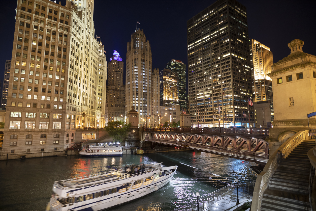 Ferry boat passes under the DuSable Bridge over the Chicago River in downtown Chicago Illinois USA during a summer night